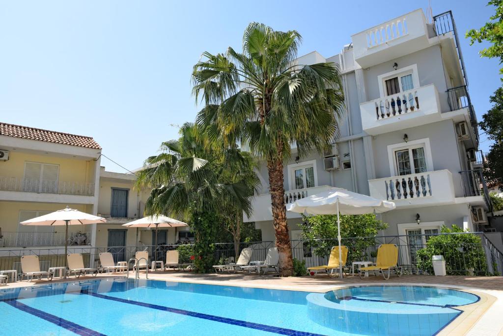 un hotel con piscina frente a un edificio en Skalidis Apartments, en Tolo