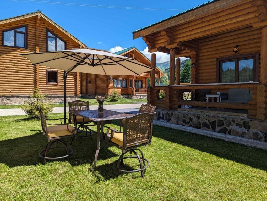 - une table avec un parasol en face d'une cabine dans l'établissement LOG HOUSE, à Bakuriani