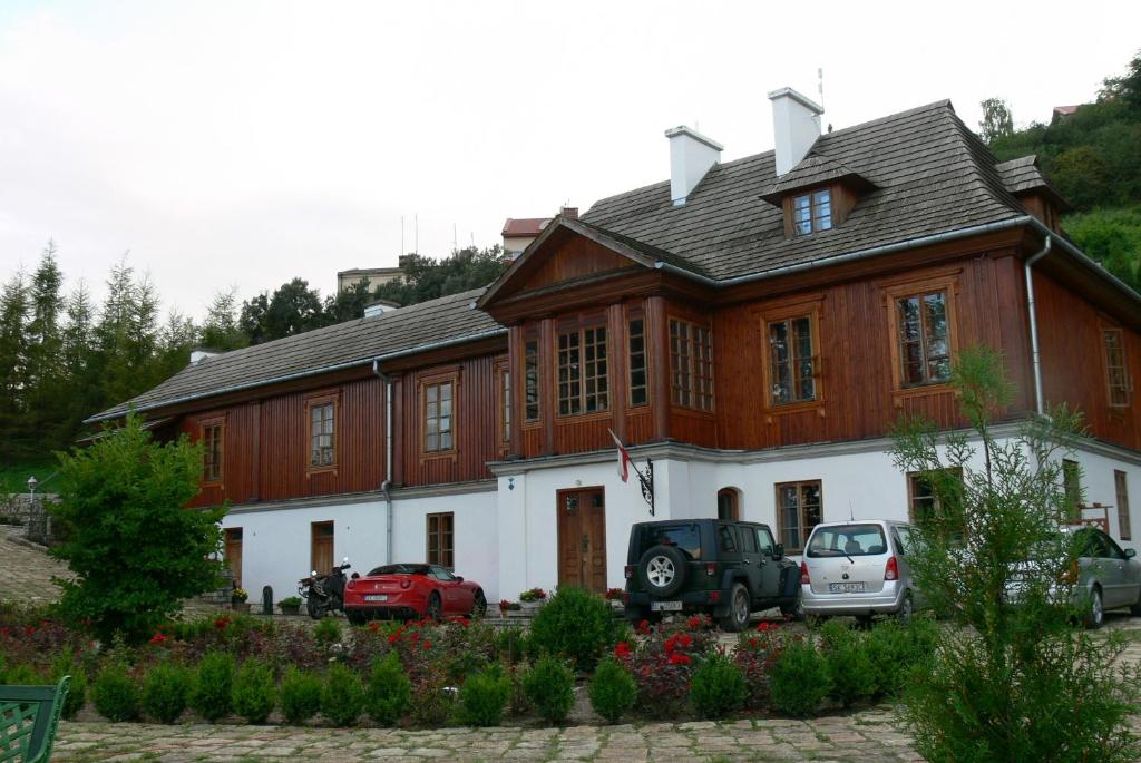 een groot houten gebouw met auto's voor het gebouw bij Dworek Karpińskich in Sandomierz