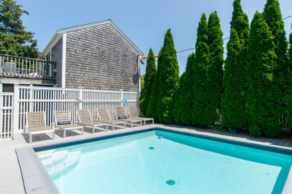 a swimming pool with chairs and trees at Condo with Wading Pool Dog Welcome in Provincetown