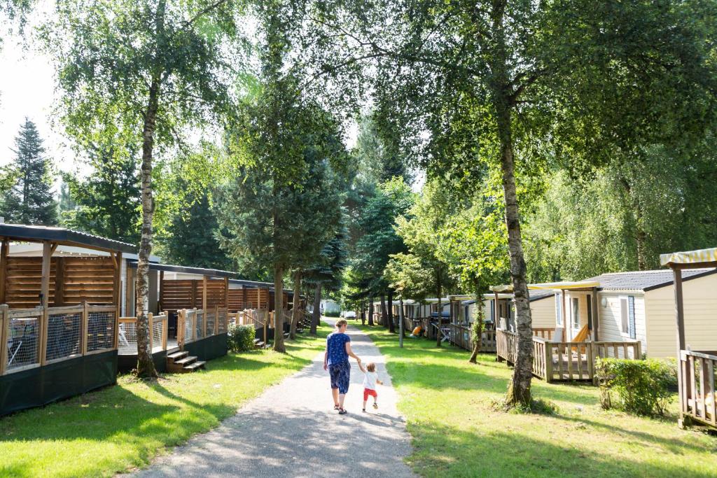 uma pessoa a passear dois cães por um caminho perto de alguns parques de campismo em hu Birkelt village em Larochette