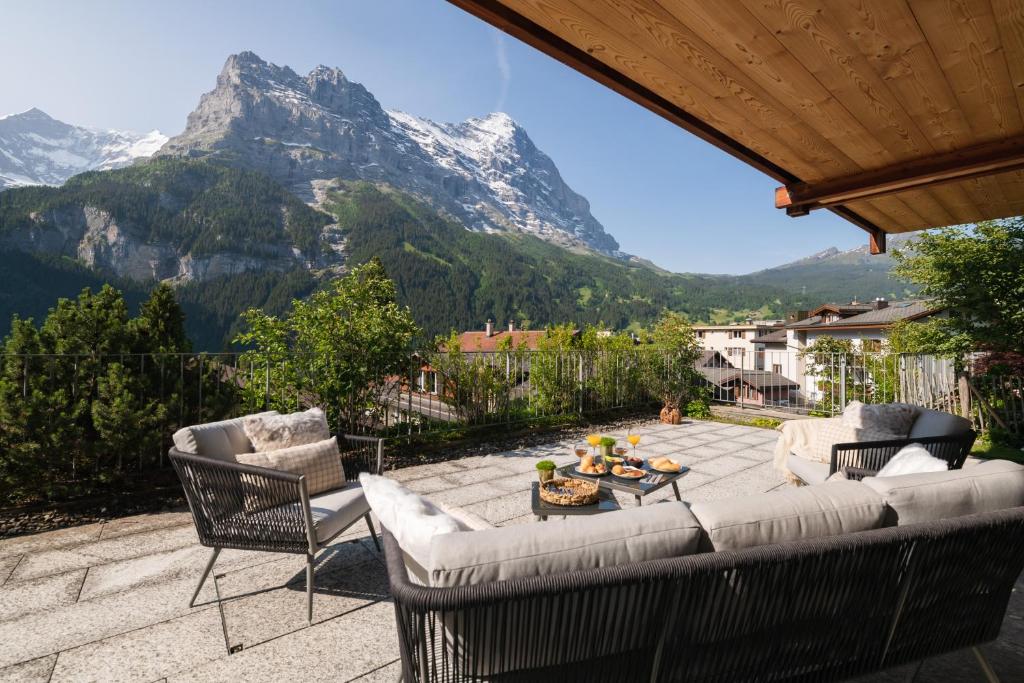 patio z kanapą i krzesłami oraz góry w obiekcie The Terrace Apartment - GRINDELHOMES w mieście Grindelwald