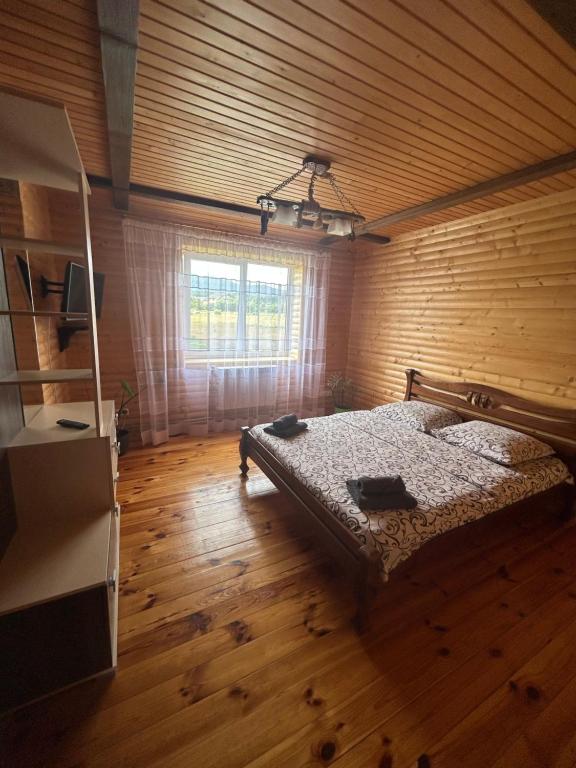 ein Schlafzimmer mit einem Bett in einem Holzzimmer in der Unterkunft Карпатські Зорі in Pilipets