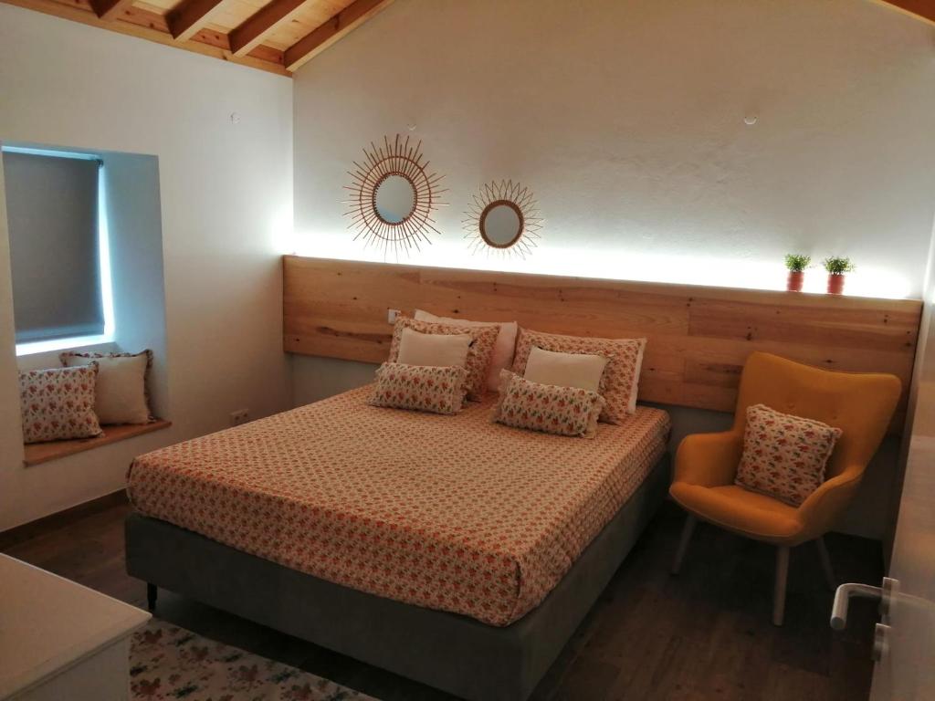 - une chambre avec un lit, une chaise et un miroir dans l'établissement Ti Chôa - Casa da Mata, à Angra do Heroísmo