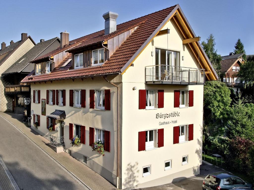 een wit gebouw met rode deuren en een bruin dak bij Gasthof Restaurant Bürgerstüble in Sankt Peter