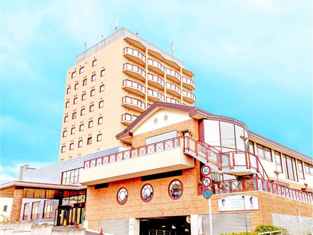 ein hohes Gebäude mit Balkon darüber in der Unterkunft Hotel BELLMARE ホテルベルマーレ in Maizuru