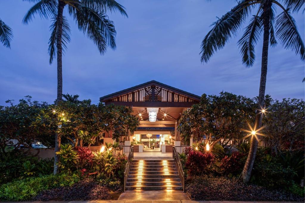 een huis met palmbomen en een loopbrug bij Sheraton Kauai Coconut Beach Resort in Kapaa