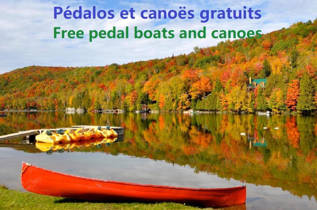 a red boat on a lake with fall foliage at Le Boisé du Lac in Mont-Tremblant