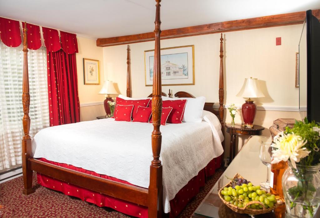 een slaapkamer met een hemelbed met rode kussens bij America's Cup Inn Newport in Newport