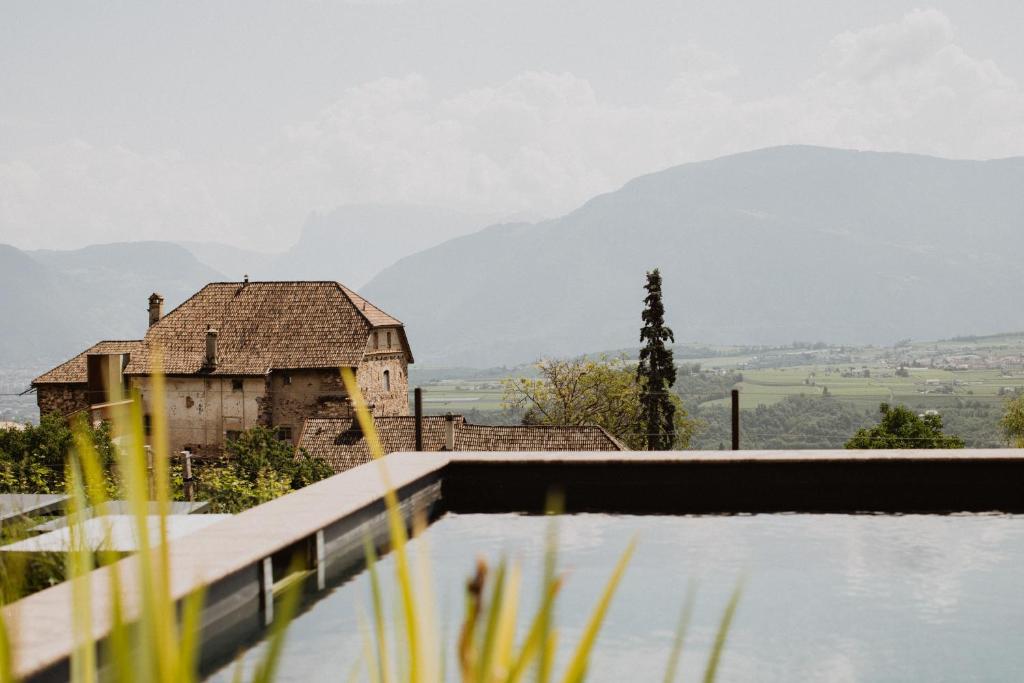 uma casa velha com uma montanha ao fundo em Ansitz Montani Eppan em Appiano sulla Strada del Vino