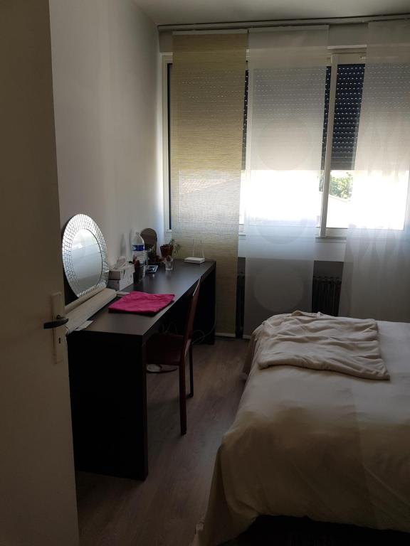 a bedroom with a desk and a bed and a window at Maison familiale avec jacuzzi et piscine in La Rochelle