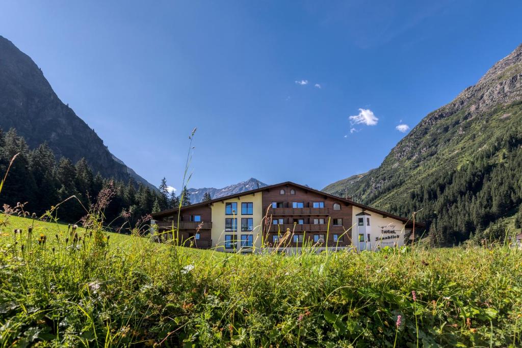 budynek na wzgórzu z górami w tle w obiekcie Hotel Sonnblick w mieście St. Leonhard im Pitztal