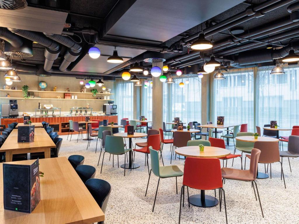 un restaurant avec des tables, des chaises et des fenêtres dans l'établissement ibis Styles Bern City, à Berne