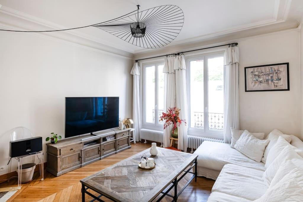 uma sala de estar com um sofá branco e uma televisão em Charmant Appartement avec Jardin em Suresnes