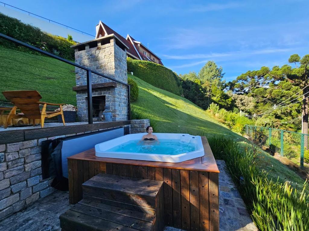 a person in a hot tub in a backyard at Pousada das Lavandas in Campos do Jordão