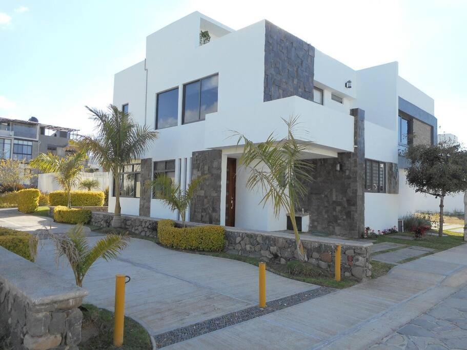 Hermosa Casa en Orilla del lago -Zona de villedos- في San Cristóbal Zapotitlán: مبنى ابيض امامه اشجار النخيل