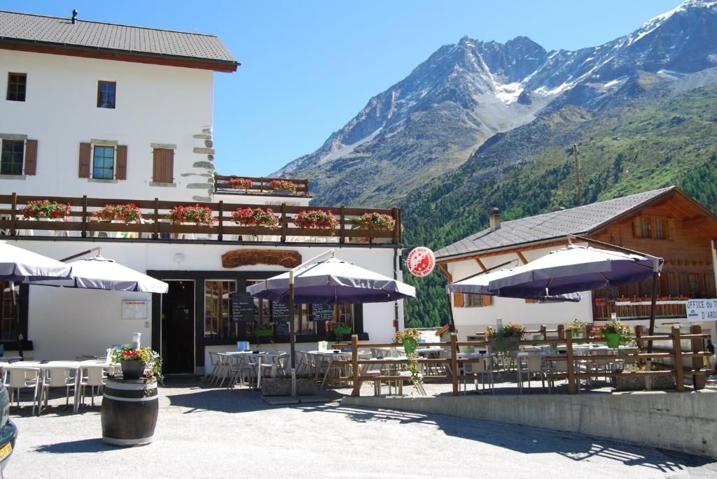 um restaurante com mesas e guarda-sóis em frente a uma montanha em Hotel du Pigne em Arolla