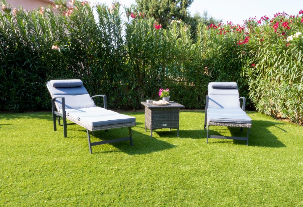 drie stoelen en een tafel in het gras bij B&B Da Laura San Teodoro in San Teodoro