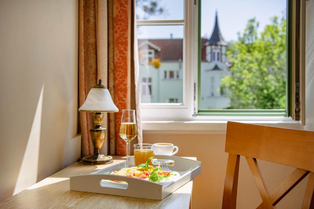 una mesa con un plato de comida y una copa de vino en Villa Sedan - Destigo Hotels, en Sopot