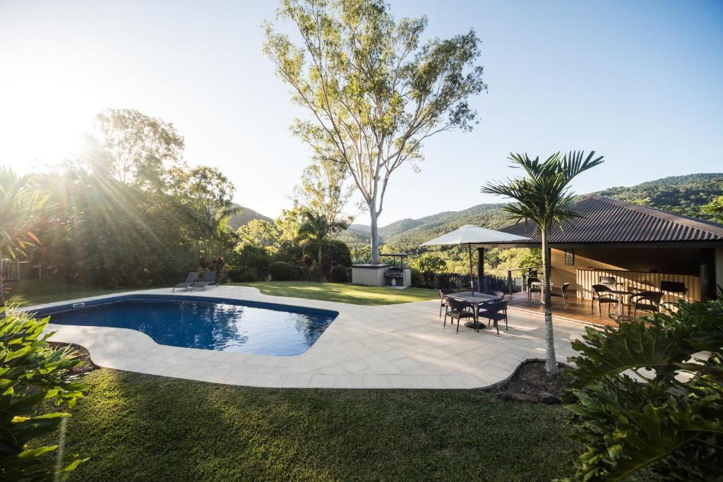 um quintal com uma piscina, uma mesa e cadeiras em Seclude Rainforest Retreat em Palm Grove