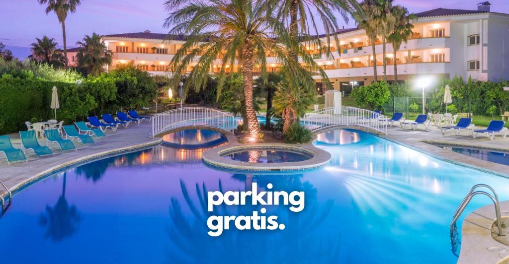 una piscina del complejo con una palmera y las palabras aparcamiento gratuito en Mas Gallau, en Cambrils