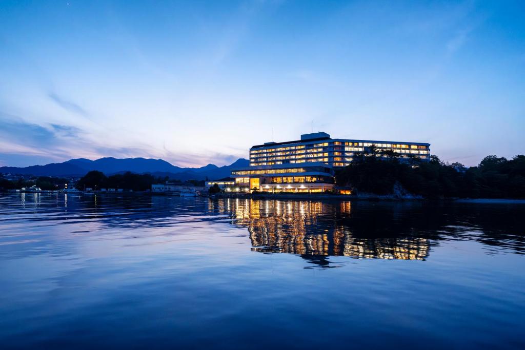 un bâtiment sur l'eau avec les lumières allumées dans l'établissement Aki Grand Hotel & Spa, à Miyajima