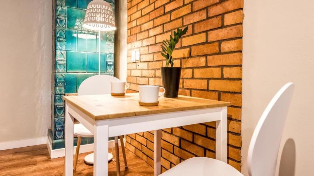 uma mesa e cadeiras num quarto com uma parede de tijolos em Flamingo Premium Hostel na Cracóvia