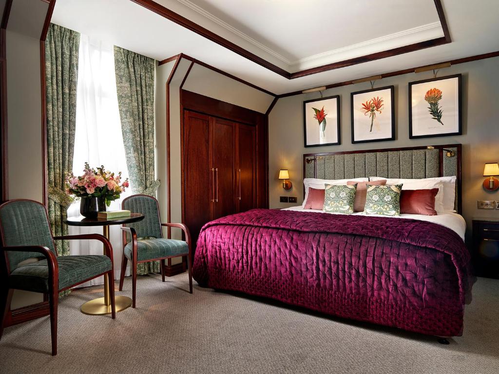 um quarto com uma cama roxa, uma mesa e cadeiras em The Stafford London em Londres