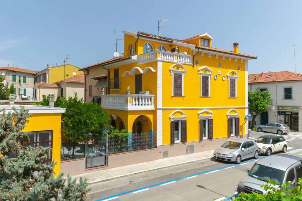 een geel gebouw met auto's ervoor geparkeerd bij La Casa di Bianca in Follonica