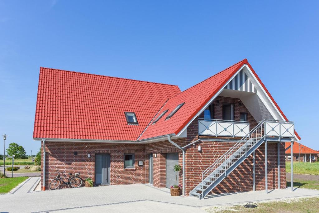 una casa de ladrillo con techo rojo y escalera en Haus Veermaster, en Neuharlingersiel