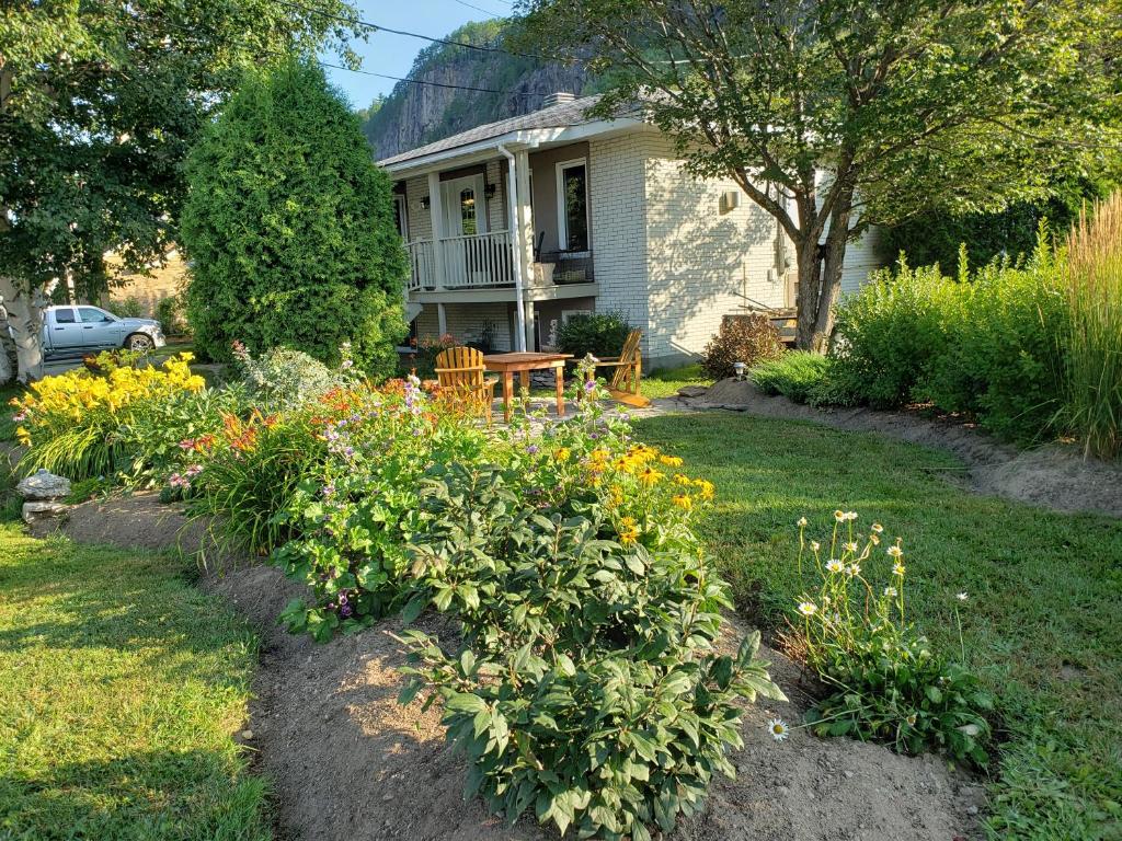 uma casa com um jardim com flores no quintal em Résidence Touristique Les Bouleaux em Petit-Saguenay