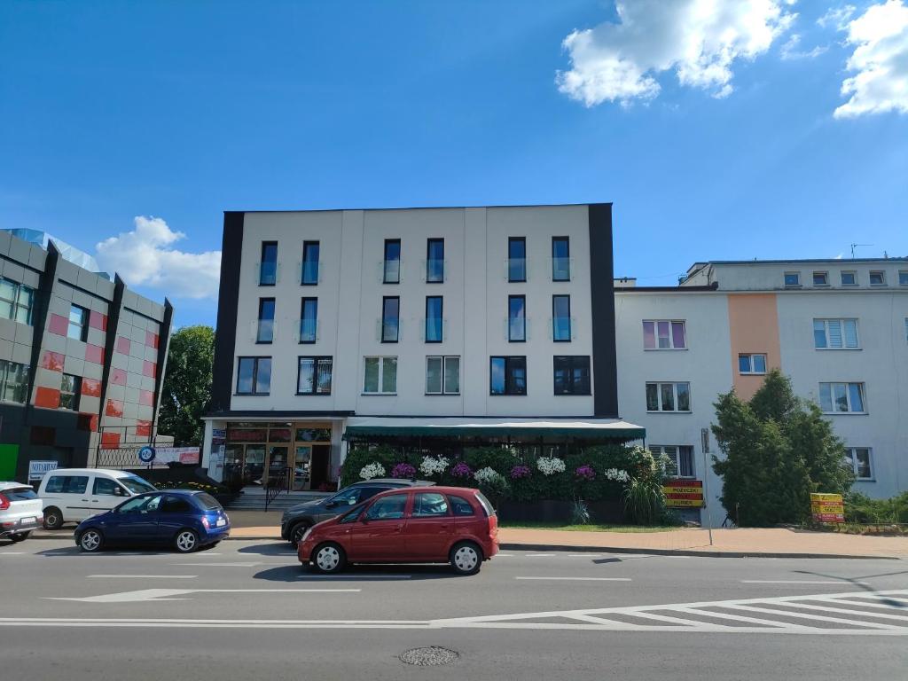 een rode auto geparkeerd op een parkeerplaats voor een gebouw bij OSCAR Obiekt Noclegowy in Sandomierz