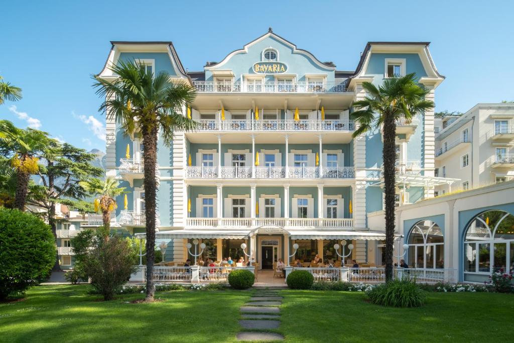 un grand bâtiment avec des palmiers devant lui dans l'établissement Villa Bavaria, à Merano