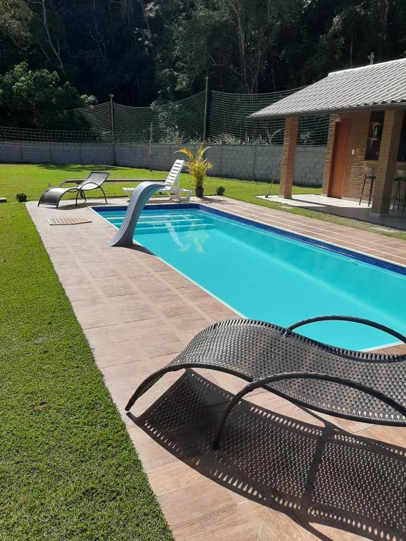 - une piscine avec 2 chaises à côté dans l'établissement Chalés Bem-me-quer Itaipava, à Itaipava