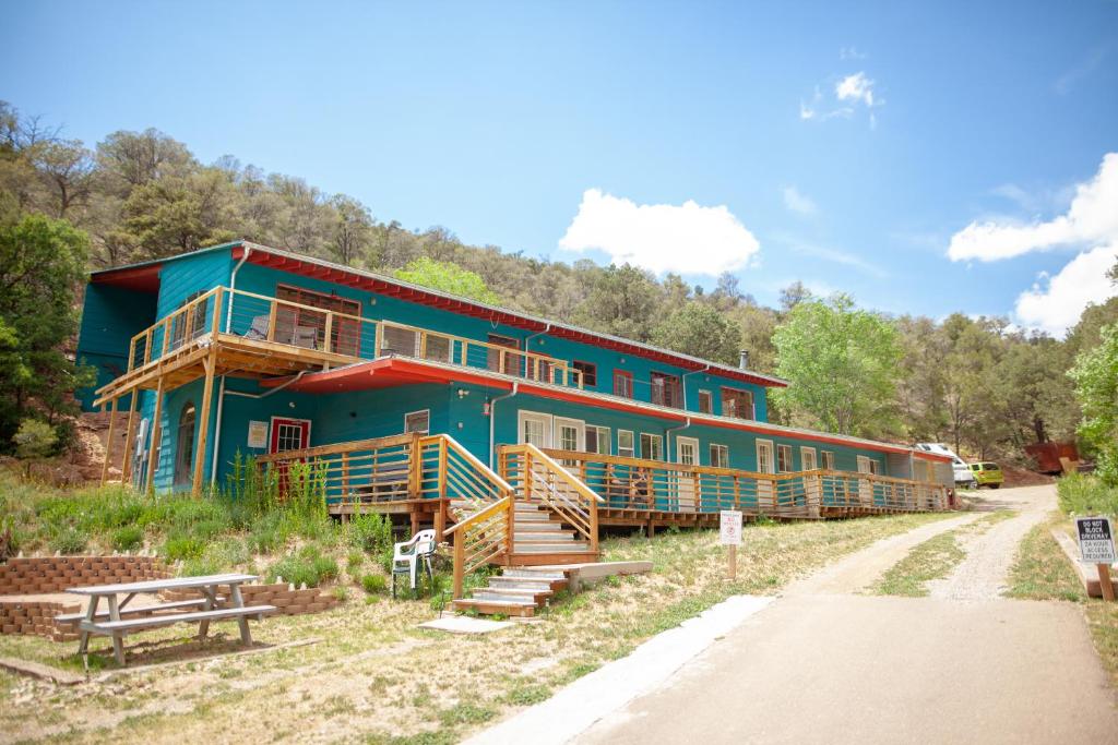 une grande maison verte sur le côté d'une route dans l'établissement Cloudcroft Hostel, à Cloudcroft