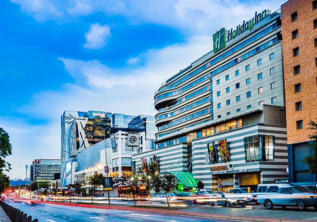 un grande edificio su una strada cittadina con le auto di Holiday Inn Johannesburg-Rosebank, an IHG Hotel a Johannesburg