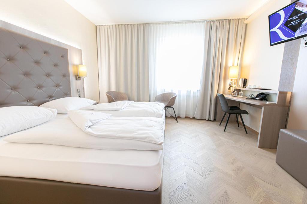 Cette chambre comprend deux lits et un bureau. dans l'établissement Das Reinisch Hotel & Restaurant, à Schwechat