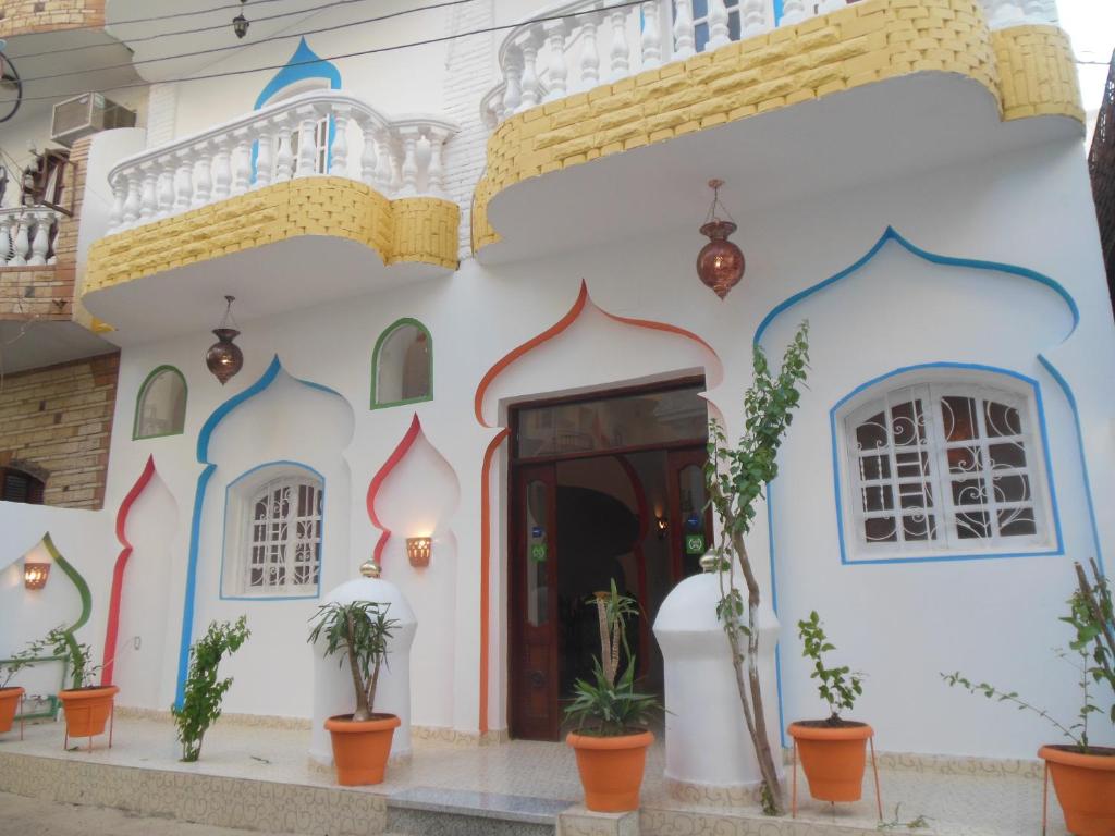 un bâtiment blanc avec une porte et des plantes en pot dans l'établissement Cleopatra Hotel Luxor, à Louxor