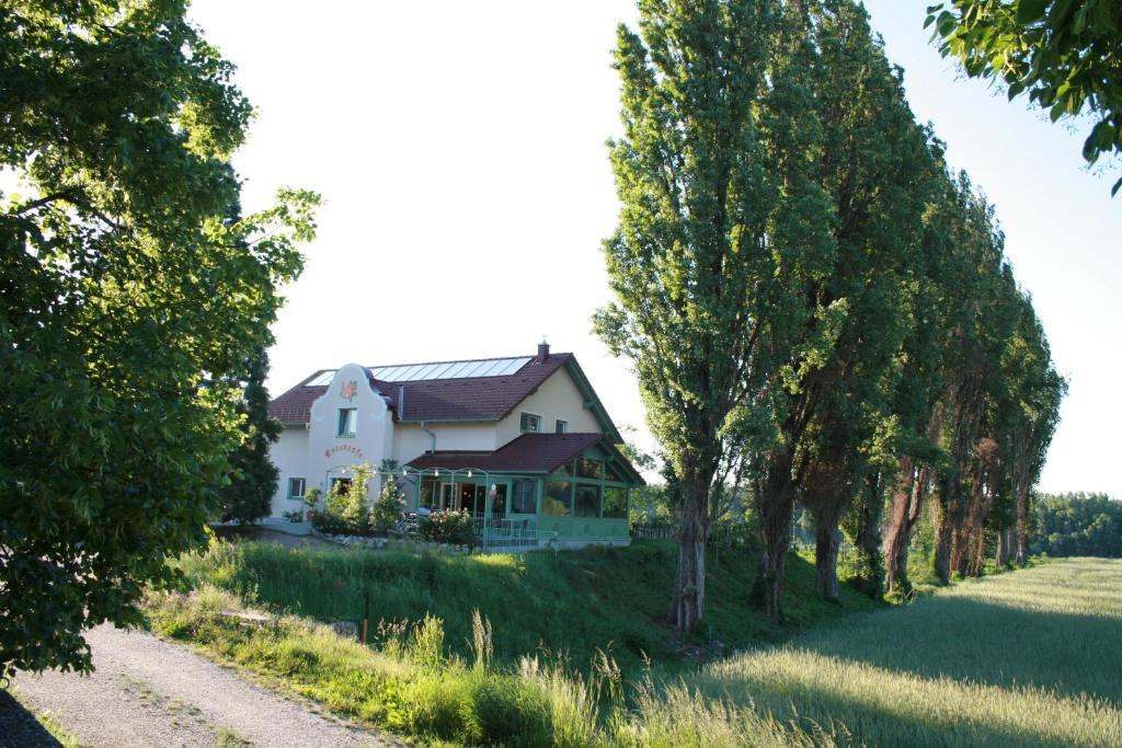 une maison blanche sur une colline avec des arbres dans l'établissement Rosenhotel - Serviced Apartments, à Zwentendorf