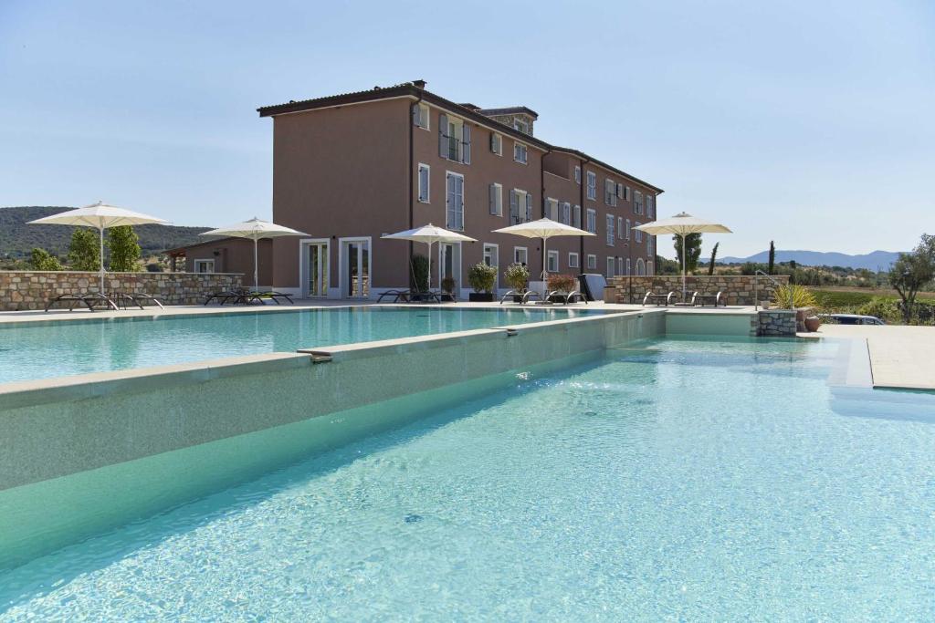 uma piscina com água azul em frente a um edifício em Riva Toscana Golf Resort & SPA em Follonica