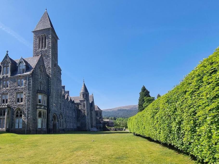 een groot stenen gebouw met een groene heg bij LOCH NESS - Luxury Highland Retreat in Scotland in Fort Augustus