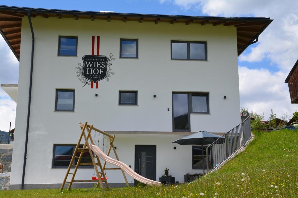 une maison blanche avec une aire de jeux devant elle dans l'établissement Appartement Wieshof, à Neukirchen am Großvenediger