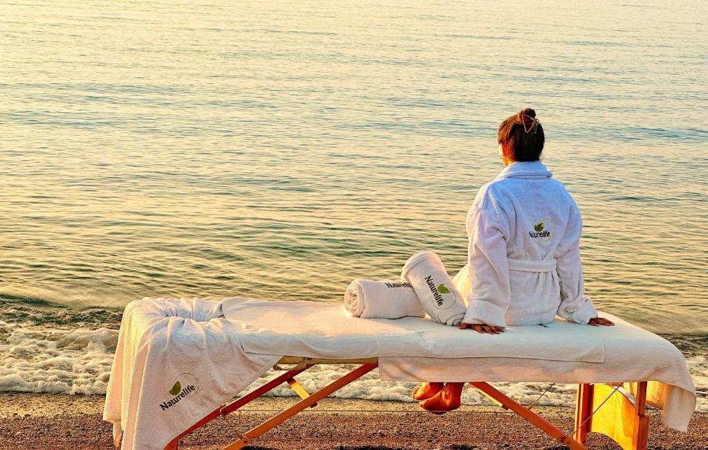 een vrouw op een bankje op het strand bij Naturelife Bungalows & SPA in Cıralı