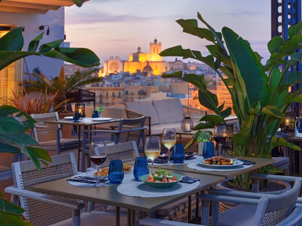 einen Tisch mit Speisen und Wein auf einem Balkon mit Aussicht in der Unterkunft H10 Imperial Tarraco 4 Sup in Tarragona