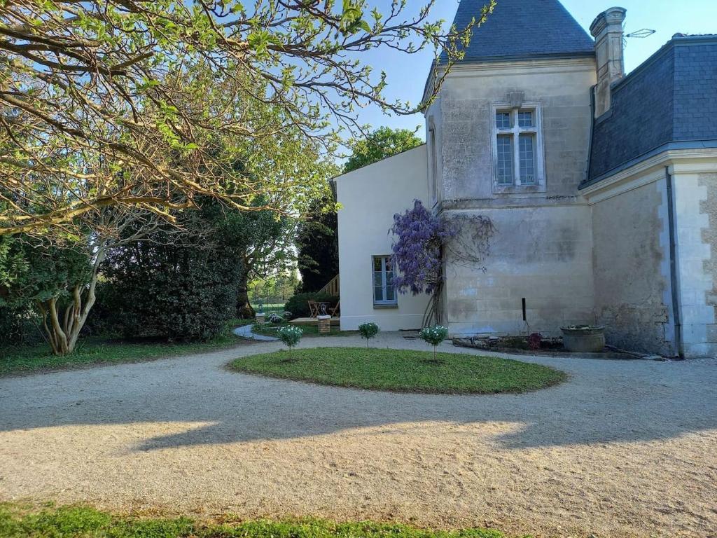 una vecchia casa in pietra con un vialetto di ghiaia di La Grelauderie 1 a Saintes