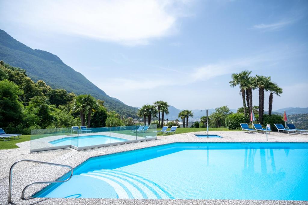 una piscina con palmeras y montañas al fondo en Centro Cadro Panoramica, en Lugano