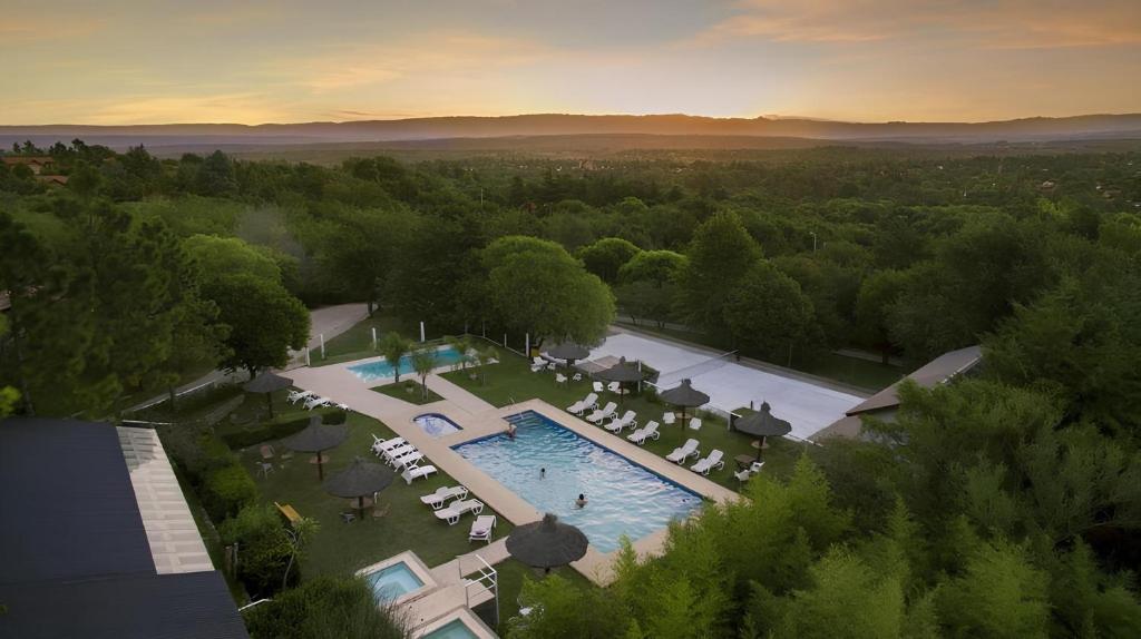 uma vista sobre uma piscina com cadeiras e árvores em Aldea de los Pajaros em Villa General Belgrano