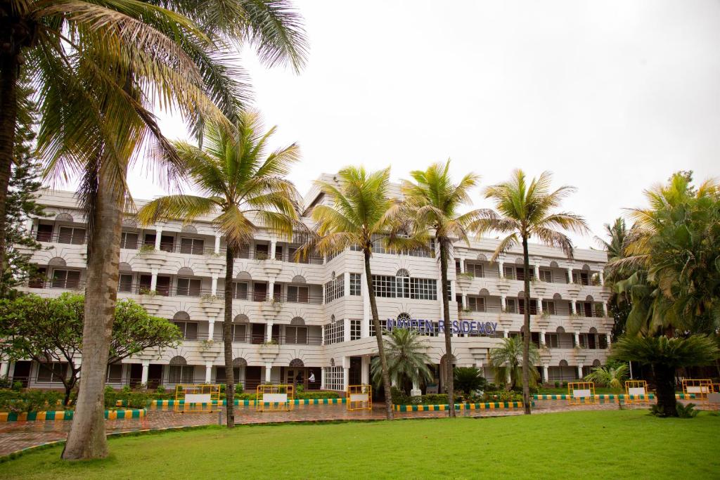 un grand bâtiment blanc avec des palmiers devant lui dans l'établissement Naveen Residency, à Amargol