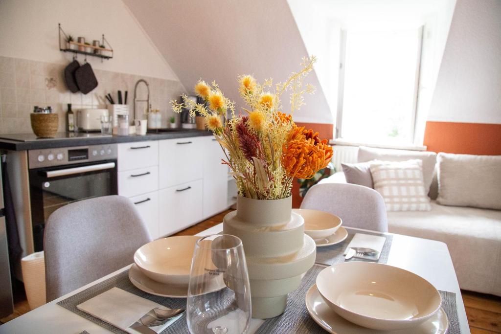 een eettafel met een vaas met bloemen erop bij Moderne Ferienwohnung mit Festungsblick im Zentrum in Königstein an der Elbe