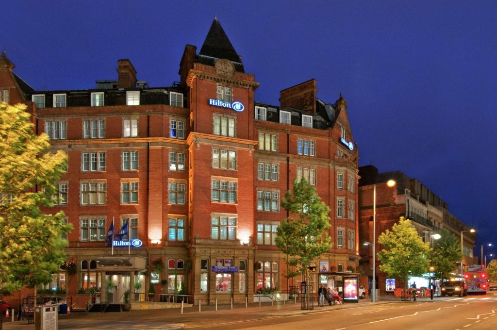 een groot bakstenen gebouw in een stadsstraat 's nachts bij Hilton Nottingham Hotel in Nottingham